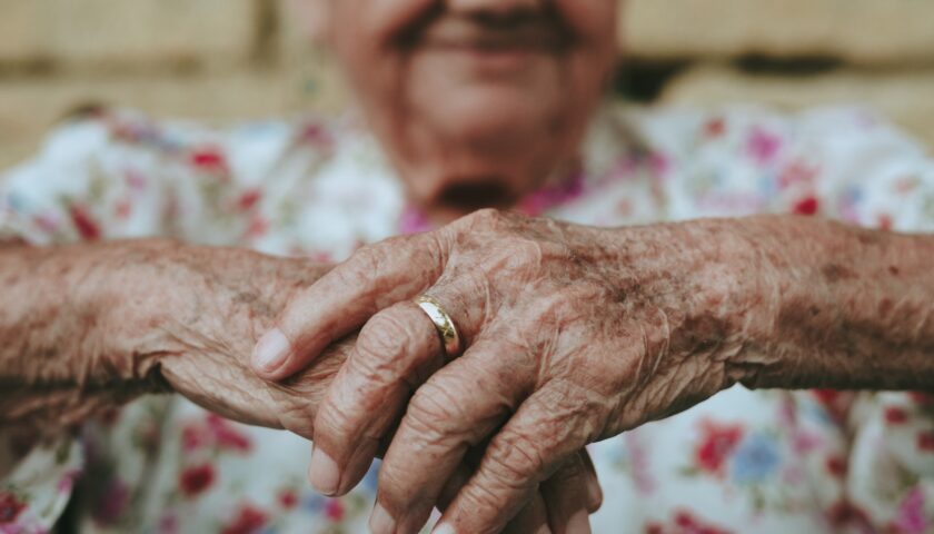 Dłonie starszej kobiety ze złotą obrączką na palcu